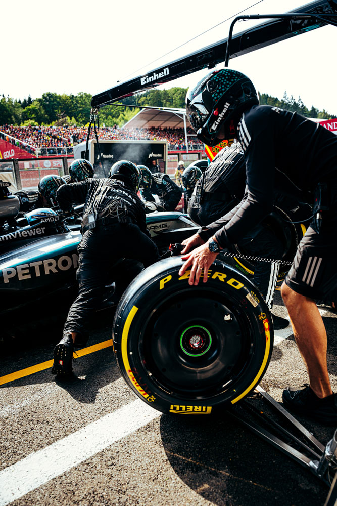 Mercedes-AMG PETRONAS Formula One Team’in mekanikleri bir pit stop gerçekleştiriyor. Bir ekip üyesi bir Pirelli lastiğini hazırlarken diğerleri araç üzerinde çalışıyor. Einhell logosu aracın üzerindeki ekipmanlarda görülüyor.