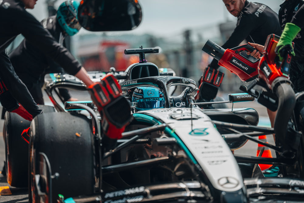 Mercedes-AMG PETRONAS Formula One Team’e ait bir araç pit stop sırasında. Ekip üyeleri, aracın parçalarını soğutmak için kablosuz Einhell üfleyiciler kullanıyor. Ekip odaklanmış ve hassas bir şekilde çalışıyor.