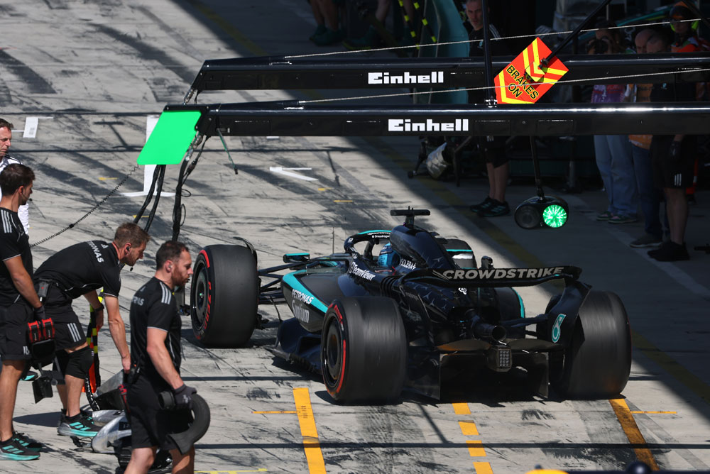 Mercedes-AMG PETRONAS Formula One Team’e ait bir araç pit alanında pit stop sırasında bulunuyor. Birkaç ekip üyesi aracın etrafında. Einhell logosu pit alanının üstünde görünüyor.