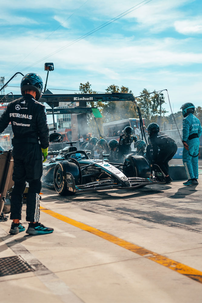 Mercedes-AMG PETRONAS Formula One Team için yoğun bir pit stop anı. Ekip harekette, lastik değiştiriyor ve aracı Einhell logolu portalın altında kontrol ediyor.