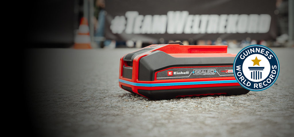 Einhell SEALED Power X-Change 4.0 Ah batarya asfaltta duruyor, sağ tarafında Guinness World Records "Record Holder" logosu ile.